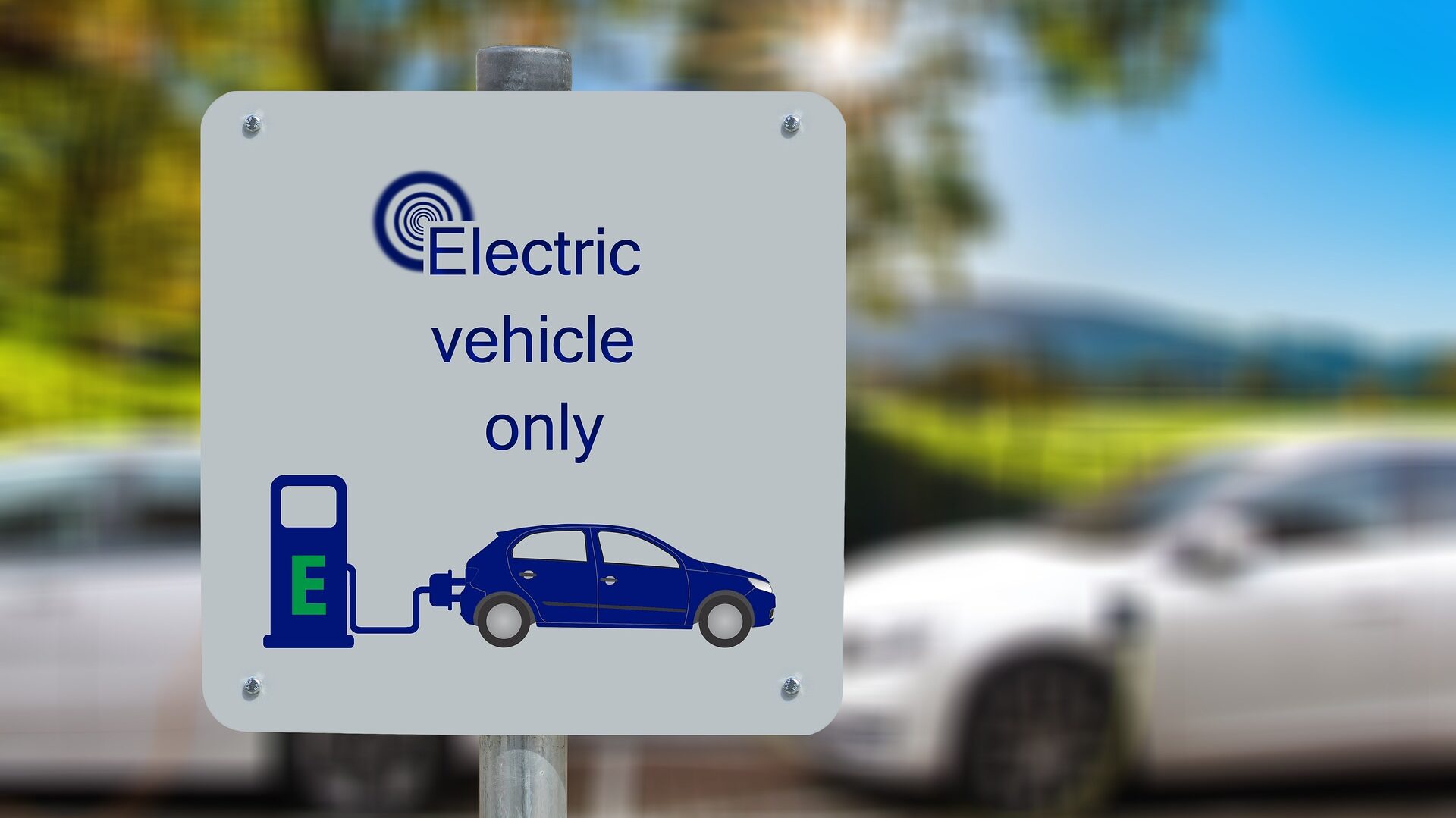Schild in englischer Sprache vor einem Parkplatz mit Ladestationen: Nur Elektrofahrzeuge erlaubt